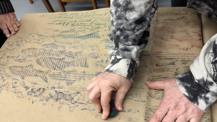 A person creating a fish rubbing